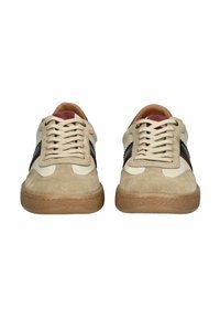 Sneaker beige e crema realizzati in materiali scamosciati e in pelle, con una striscia di accento nera e rossa, punta rotonda e suola in gomma testurizzata.