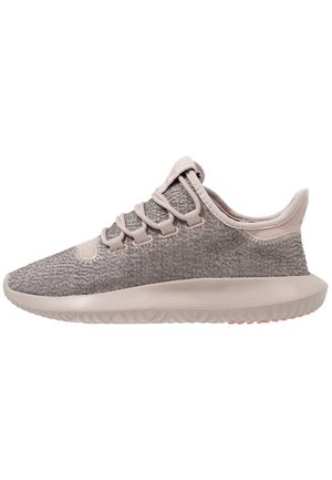 Lysebrun strik sneakers med tyk sål, snørelukning foran og polstret ankelkrave, set fra siden på en hvid baggrund.