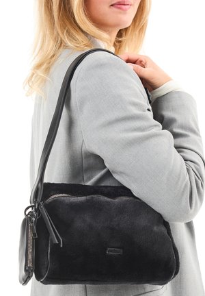 Schwarze Fettleder-Handtasche mit strukturiertem Design, ausgestattet mit einem oberen Reißverschluss und Lederakzenten. Wird über der Schulter mit einem schmalen Tragegurt getragen.