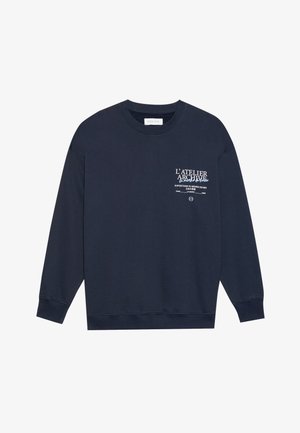 Sudadera azul marino de algodón. Presenta mangas largas, un cuello redondo y texto impreso en la parte frontal. Textura suave y corte relajado.