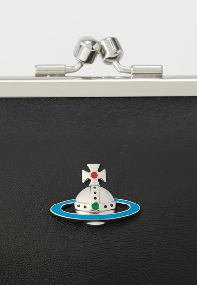 Crna torbica od teksturiranog materijala sa srebrnim kopčom, ukrašena emblemom krune okružene plavim prstenom i obojenim detaljima.