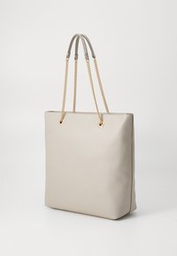 Beige leather tote bag with a structured shape and gold chain straps. Features two top handles and metal eyelets for attachment.