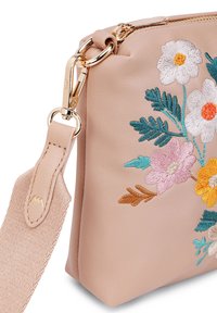 Růžová kožená taška s květinovou výšivkou v bílé, žluté a tyrkysové barvě. Obsahuje zlatý zip a kovové sponky. Součástí je texturovaný popruh.