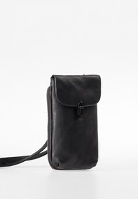 Borsa a tracolla in pelle nera con chiusura a pattina e zip laterale. Tessuto liscio, design minimale e tracolla regolabile.