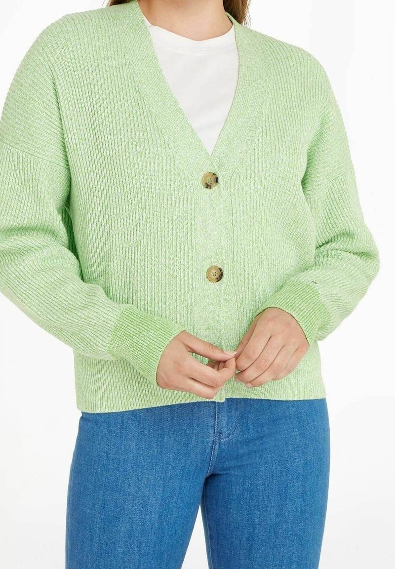 Cardigan a coste verde chiaro con scollo a V, dotato di due grandi bottoni marroni e maniche lunghe. Il tessuto a maglia testurizzato aggiunge profondità.