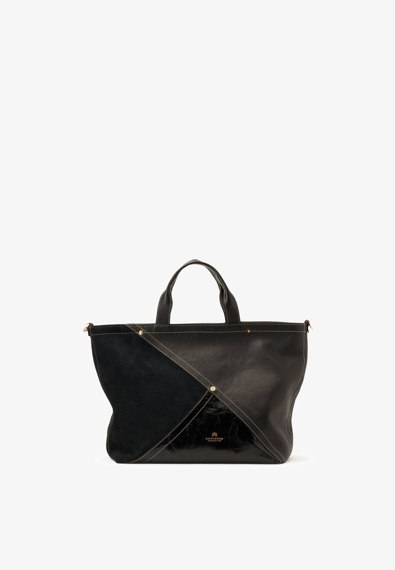 Sac cabas noir avec poignées supérieures, présentant un patchwork diagonal de textures en cuir lisse, grainé et suédé, avec des accents de rivets dorés.