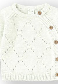 Cárdigan de bebé tejido color crema con patrón de diamantes, cuello redondo y botones de madera a lo largo de la abertura lateral.