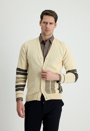 Cárdigan de color beige claro con un tejido texturizado, que presenta acentos de rayas marrón oscuro en las mangas. Con cinco botones y un diseño de cuello en V.