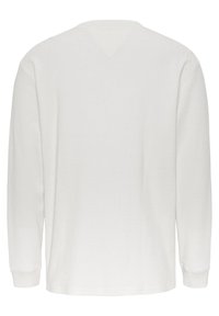 Bílé termo tričko s dlouhými rukávy, texturovaným vaflovým vzorem, kulatým límcem a žebrovanými manžetami. Zadní strana je jednoduchá a nezdobená.