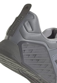 Chaussures de sport gris foncé avec tige en maille texturée, talon renforcé et semelle en caoutchouc avec un motif de bande en zigzag.
