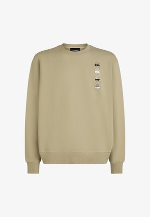 Kaki dukserica napravljena od mekog vlakna s okruglim izrezom, rebrastim manžetama i pet otisnutih lica sprijeda u različitim stilovima.