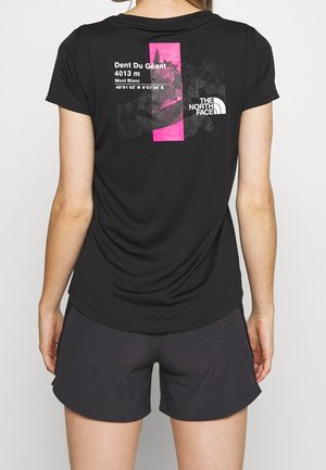 Nainen, jolla on mustat shortsit ja musta T-paita, jossa on vaaleanpunainen ja valkoinen vuoristokuvio sekä The North Face -logo takana.