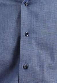 Niebieska, tkana koszula z wzorem w jodełkę, sześcioma ciemnymi guzikami i gładką teksturą. Materiał wydaje się lekki i przewiewny.