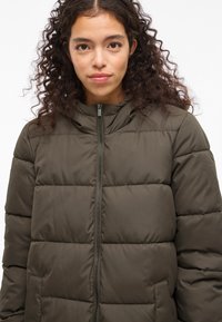 Olijfgroene donzen jas met capuchon, voorzien van een ritssluiting aan de voorkant, een doorgestikt patroon en twee zijzakken.