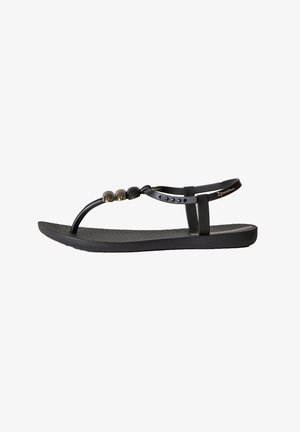 Chanclas negras con una suela texturizada, un diseño de tiras minimalista y acentos decorativos de cuentas en la parte superior.