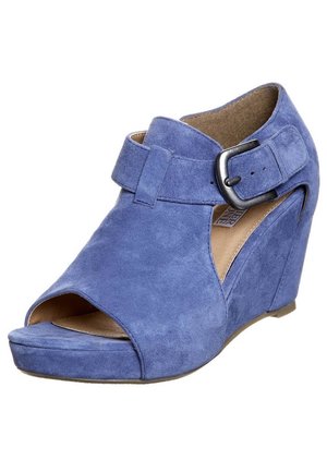 Blauwe suède wedge sandaal met open teen, brede band bij de enkel en een zilveren gespdetail. Zachte textuur en gebogen ontwerp.