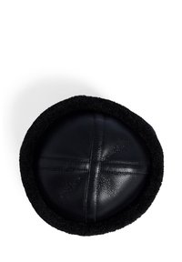 Juodas odinis kepurėlis su tekstūruotu juodu pūkuotu apvadu, parodytas viršaus ant balto fono.