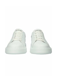 Een paar witte Blackstone laag uitgesneden sneakers met witte veters, dikke rubberen zolen en een minimalistisch ontwerp, gezien vanaf de voorkant.