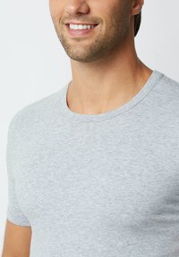 T-shirt grigio a maniche corte realizzato in tessuto morbido, con collo a giro. Texture liscia e semplice, senza fantasie.