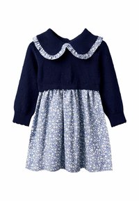 Strickpullover in Marineblau mit einem gerafften blumigen Kragen, kombiniert mit einem blauen Rock mit weißen Blumenmustern, langen Ärmeln und einem gerafften Bund.