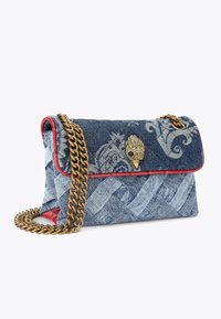 Borsa in denim con profili rossi e tracolla in catena dorata. Presenta motivi intricati e una chiusura decorativa dorata a forma di mano.