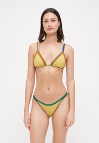 Bikini giallo con top triangolare e slip coordinato. Presenta cuciture decorative multicolori e tessuto lucido con copertura minimale.