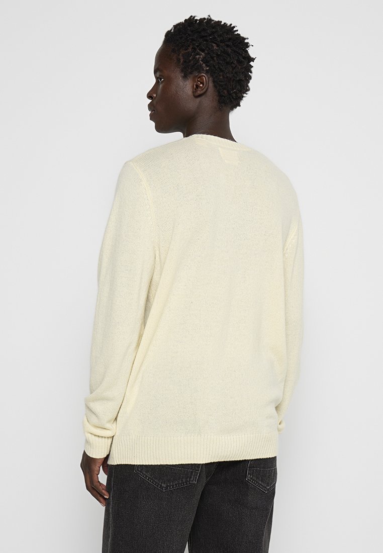 Maglione a maglia giallo chiaro con maniche lunghe, orli a costine e una vestibilità rilassata, caratterizzato da una superficie testurizzata e un semplice design sul retro.