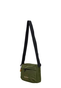 Bolso bandolera de tela verde con una correa negra, con cierre de cremallera y un detalle de logo en el frente. Forma compacta y rectangular.