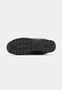 Suola di scarpa in gomma nera caratterizzata da profondi battistrada, scanalature e motivi circolari per una presa efficace. Materiale resistente con un design robusto.
