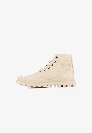 Beżowe sneakersy typu high-top wykonane z miękkiego zamszu, z okrągłymi czarnymi oczkami, teksturowaną boczną panelem oraz gumową podeszwą z wypustkami dla lepszej przyczepności.