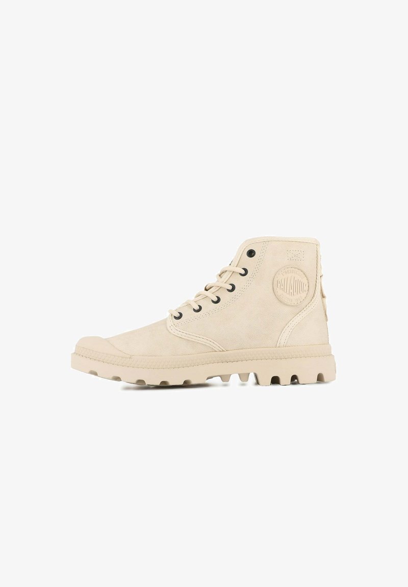 Zapatillas de caña alta beige hechas de suave ante, con ojales negros redondos, un panel lateral texturizado y una suela de goma con clavos de agarre.