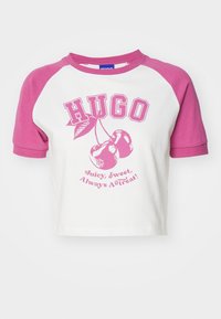 Camiseta de cultivo de algodón blanca con mangas raglán rosas. Presenta un gráfico de cereza y el texto "HUGO Jugoso, Dulce, ¡Siempre un Regalo!" en rosa.