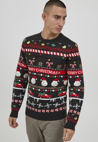 Strikket julesweater med svart bunn, med fargerike snømenn, sukkert�øystokker og festlige mønstre i rødt, grønt og hvitt. Rund hals.