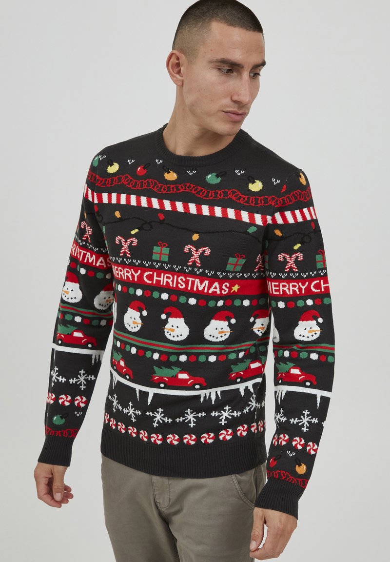 Pull de Noël en tricot avec une base noire, orné de bonhommes de neige colorés, de cannes en sucre et de motifs festifs en rouge, vert et blanc. Col rond.