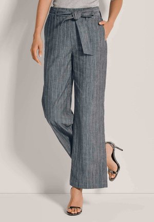 Grijze wijde broek met een opgelegde tailleband, voorzien van verticale strepen en een gestructureerde stof. Gecombineerd met zwarte hoge hakken sandalen.