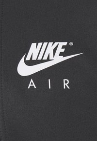 Svart tyg med en vit Nike-logotyp och texten "AIR", med en jämn, matt yta och en sportig design.