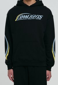 Czarna bluza z kapturem z napisem "LOWLIGHTS ENHANCED RACING GEAR". Charakteryzuje się niebieskimi i żółtymi ukośnymi akcentami na rękawach. Z przodu kieszeń kangurkowa.