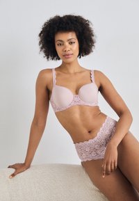 Light pink lace bra with scalloped edges and matching lace shorts, featuring a smooth cup design and decorative accents at the waistband.