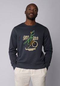 Marineblauwe sweatshirt met een dinosaurusschildering die op een fiets rijdt. Heeft ribbelmanchetten en een ribbelhalslijn, zachte stof en een hedendaags ontwerp.