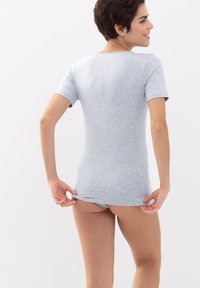 Top grigio a maniche corte con una texture morbida e liscia. Design aderente, colletto rotondo e orlo posteriore leggermente più lungo. Abbinato a pantaloni corti coordinati.