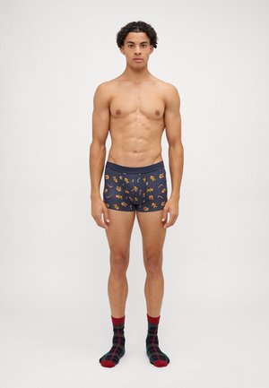 Boxer da uomo blu navy con motivi colorati di fiori e forme geometriche, abbinati a calzini a scacchi neri e rossi.