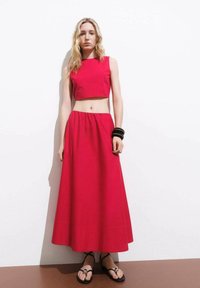 Completo rosso in due pezzi composto da un top corto e una lunga gonna fluida. Realizzato in un tessuto morbido con un design semplice e vita elastica.