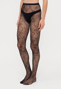 Zwarte visnetpanty's met een bloemmotief, doorschijnende textuur en een hoog tailleontwerp, met open tenen bij de voeten.