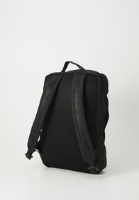 Sac à dos noir avec panneau arrière en mesh rembourré et bretelles réglables. Comprend une poignée sur le dessus et un design épuré sans matériel supplémentaire.