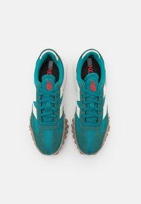 Gröna och vita sneakers med mesh och mocka, rundad tå, tjock gummisula med bra grepp och framträdande logotyp i röd.