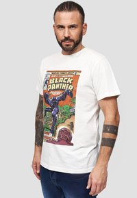 Vit bomullströja med en färgglad vintage Black Panther serietidningstryck. Korta ärmar, rund halsringning, med en avslappnad passform och mjuk textur.