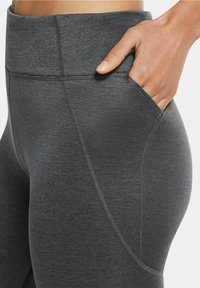 Leggings sportivi grigi con vita alta, dotati di una tasca laterale e una texture liscia, accentuati da cuciture piatte per il comfort.