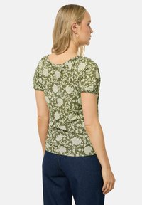 Zielony t-shirt w kwiaty z krótkimi bufiastymi rękawami, z okrągłym dekoltem i dopasowanym krojem, wykonany z miękkiego, lekkiego materiału.