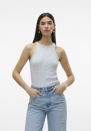 Gray sleeveless top with a high neckline, paired with light blue distressed jeans. Model stands with hands in pockets against a plain background.