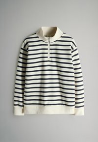 Pruhovaný svetr v krémové a námořnické modři, má límec na půl zip, žebrované manžety a měkkou texturu. Vertikální pruhy vytvářejí jednotný vzor.